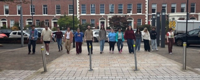 A number of students walking forward together in a straight line